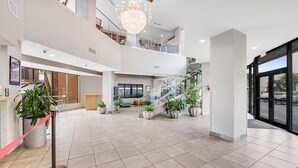 A spacious lobby with a staircase, potted plants, and a chandelier. - Rare find! Ocean front bedroom, Pet friendly! (Myrtle Beach)