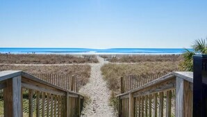 A wooden pathway leading to a beach with a clear view of the ocean. - Rare find! Ocean front bedroom, Pet friendly! (Myrtle Beach)