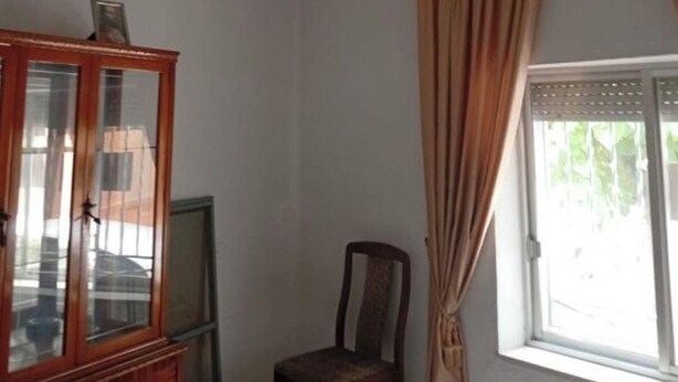 Una habitación con techo estampado, un armario de madera, una silla y una ventana con cortinas.
