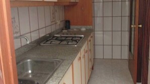 Cocina con gabinetes blancos, estufa a gas y un lavamanos.