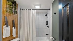 A bathroom with a toilet, sink, shower, and a door.