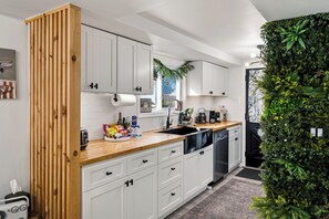 A modern kitchen with white cabinets, a wooden countertop, and a green wall. - Summit Home - The Ultimate Summit of Style for 12 (Tobyhanna)
