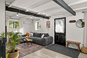 A modern living room with a grey sofa, a coffee table with a vase, a black door, and a window with curtains. - Summit Home - The Ultimate Summit of Style for 12 (Tobyhanna)