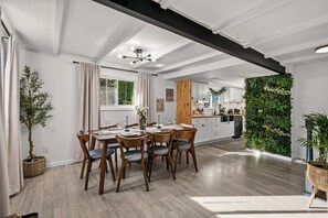 Una cocina moderna con armarios blancos, una mesa de comedor de madera y un jardín vertical verde.