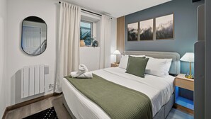 A modern bedroom with a large bed, bedside tables, a mirror, and a window with curtains.