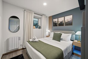 Un dormitorio moderno con una cama grande, mesitas de noche, un espejo y una ventana con cortinas.