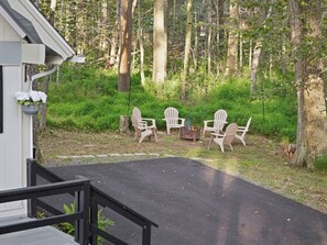 A deck with outdoor seating and a fire pit, surrounded by a forested area. - Summit Home - The Ultimate Summit of Style for 12 (Tobyhanna)