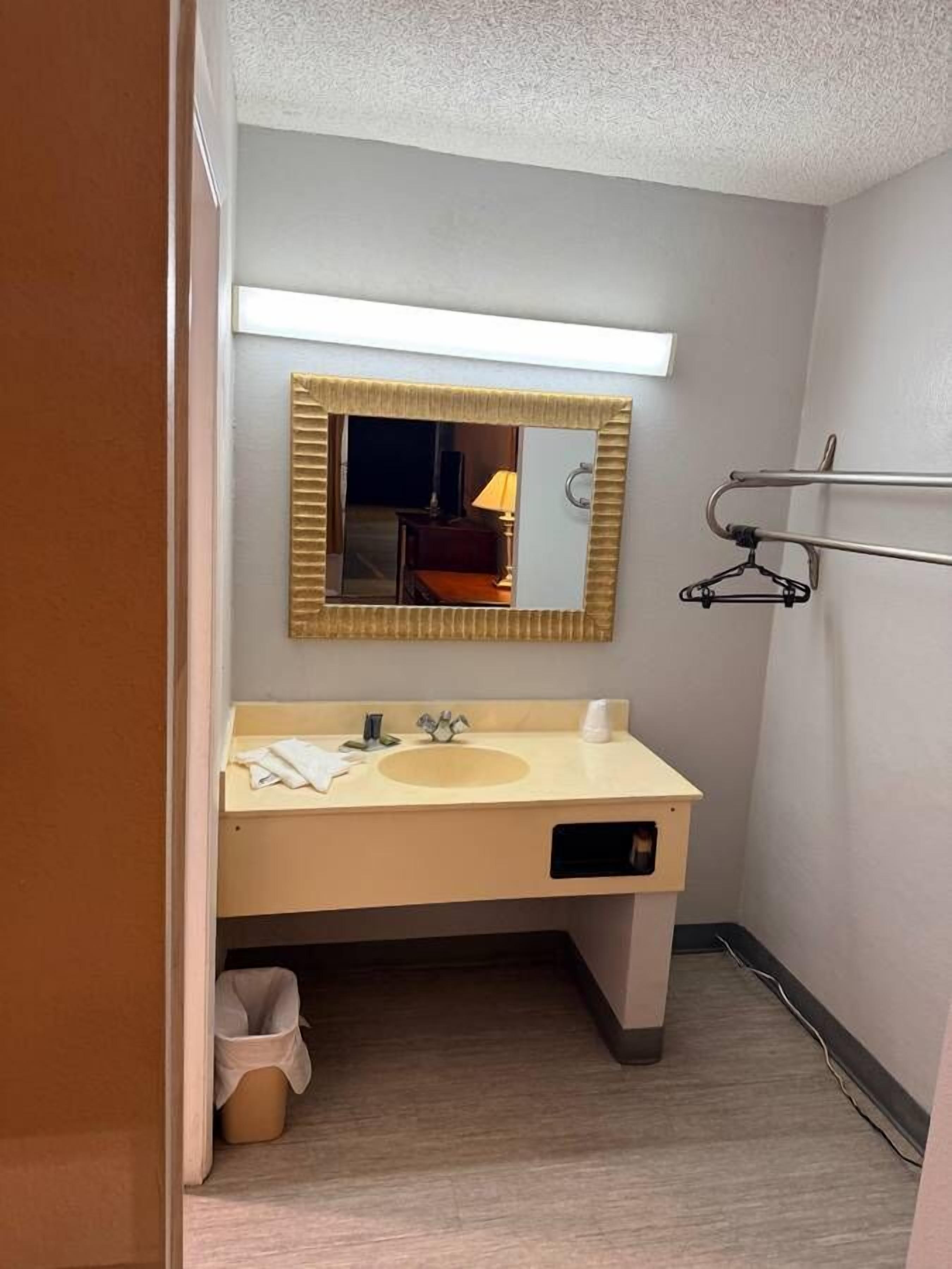 Un baño pequeño con lavamanos, espejo y perchero para toallas.