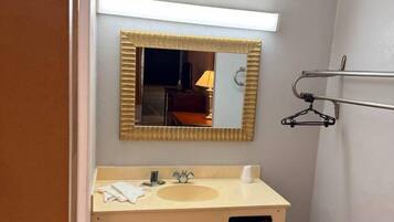 Un baño pequeño con lavamanos, espejo y perchero para toallas.