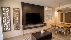 A modern living room with a flat-screen TV, wooden furniture, and decorative panels. - Stay & Relax: Fully Equipped Loft in Los Cabos (Cabo San Lucas)