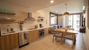 A modern kitchen with wooden cabinets, a built-in oven, and a dining area with a wooden table and chairs. - Stay & Relax: Fully Equipped Loft in Los Cabos (Cabo San Lucas)
