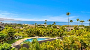 A resort with a swimming pool surrounded by lush greenery and palm trees, overlooking a scenic ocean view. - Luxurious Wailea Oceanview Resort Vistas (Kihei)