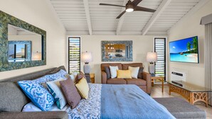 A spacious bedroom with a large bed, a sofa, a TV, and a ceiling fan. - Luxurious Wailea Oceanview Resort Vistas (Kihei)