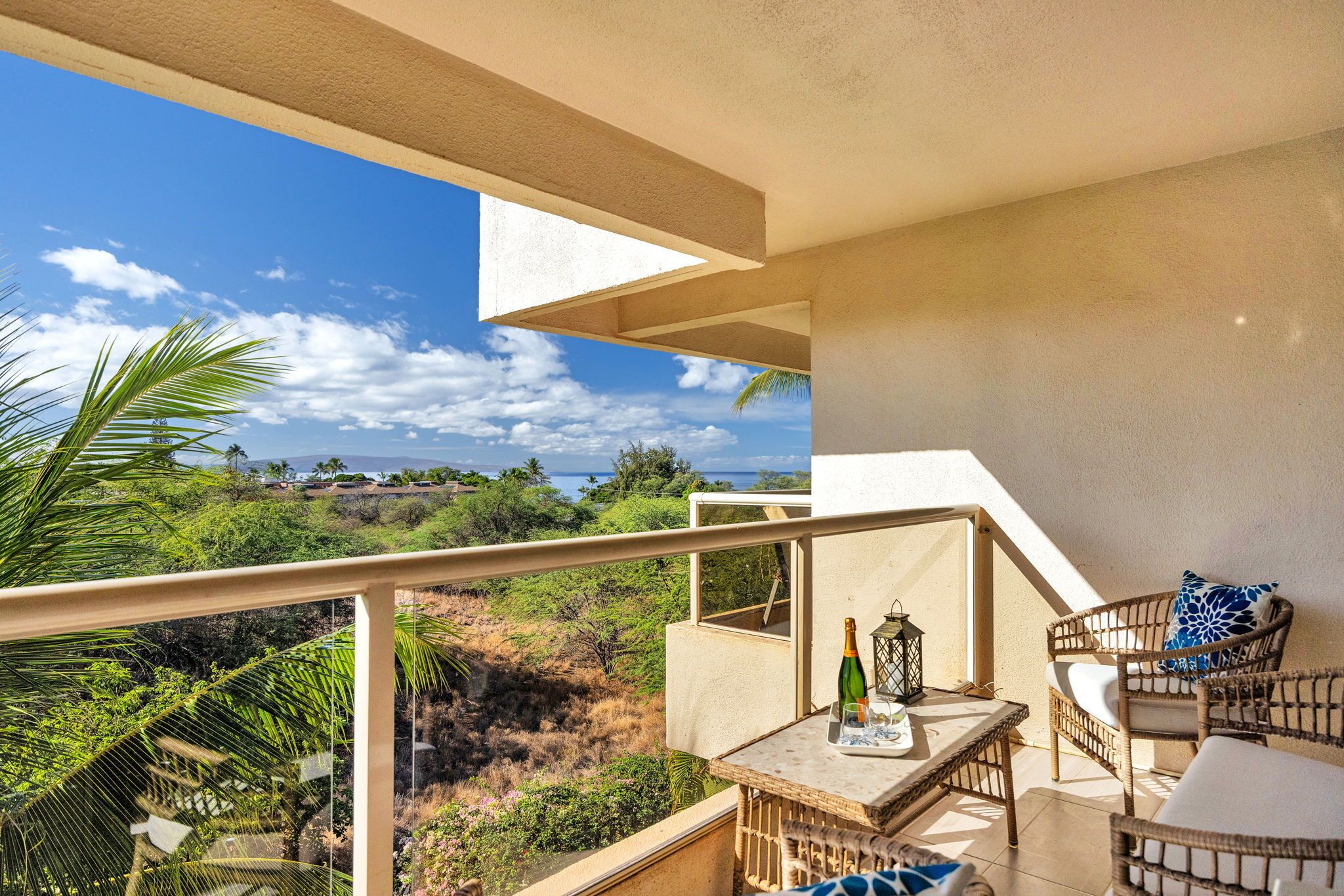 A balcony with a table, chairs, and a bottle of champagne.