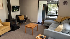 Ein Wohnzimmer mit einer Couch, einem Sessel, einem Holztisch und einem schwarzen Kaminofen.
