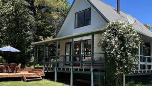 Ein Haus mit einer großen Terrasse, einem Schornstein und einem überdachten Sitzbereich im Freien.