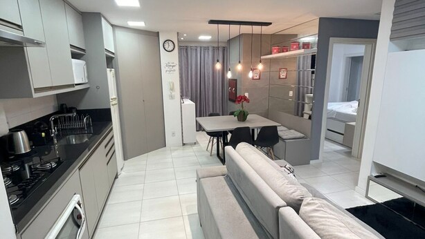 A modern kitchen with a dining area, a built-in sofa, and a separate sleeping area.