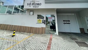 A tall residential building named "VÔ PEDRO" with a modern design, featuring a brick-paved entrance and a clear sky in the background.