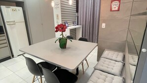 A compact kitchen with a dining table, chairs, and a built-in bench with cushions.