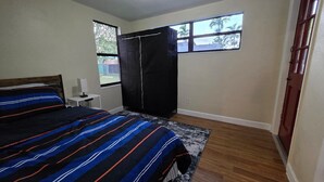 Une chambre à coucher avec un lit, un bureau, une fenêtre et une porte.