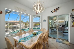 A dining area with a view of a pool and boats, a chandelier, and a lizard decoration. - Boaters Dream Pool Spa Dock Walking Biking (Palm Coast)