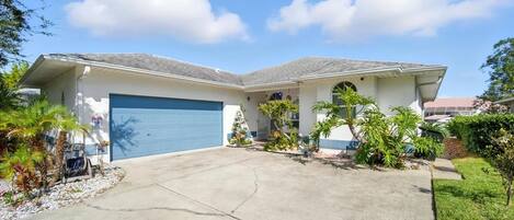 A two-story house with a blue garage door, a covered front porch, and a driveway.