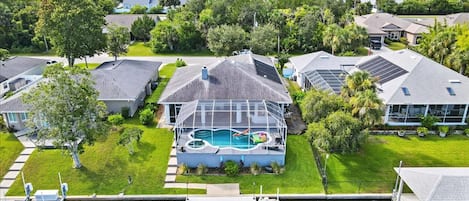 A residential property with a swimming pool, solar panels, and a dock.