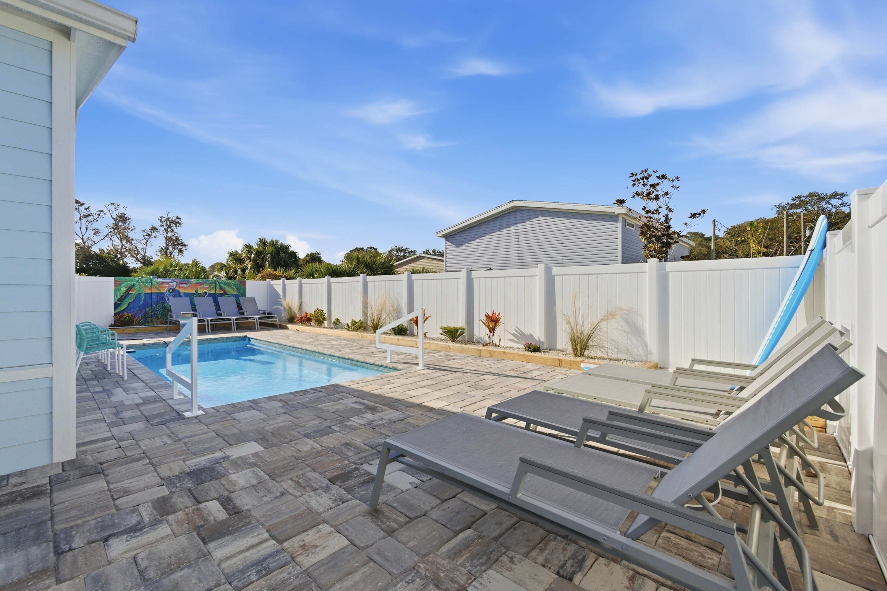 A backyard with a swimming pool, lounge chairs, and a slide.