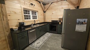 A compact kitchen with wooden walls, a refrigerator, a coffee maker, and a window.