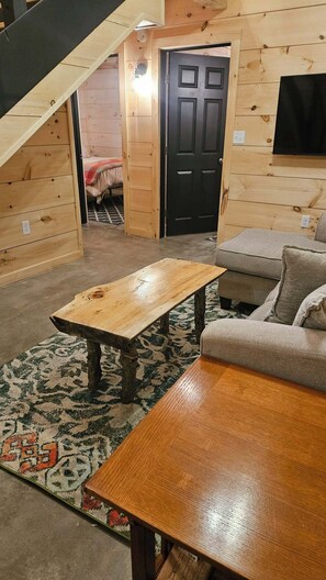 Une pièce chaleureuse avec un plancher en bois, un canapé, une table basse et un escalier menant à une autre pièce.