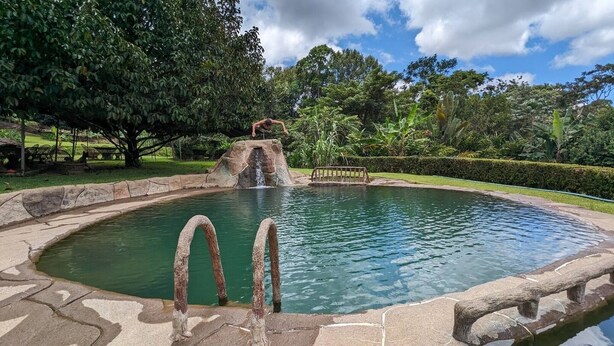 A circular pool with a stone border and a waterfall feature in the center. - Savegre River Cabina + Mediterranean Food (Savegre)