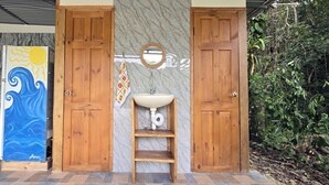 A bathroom with wooden doors, a sink, and a towel rack. - Savegre River Cabina + Mediterranean Food (Savegre)