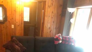 Ein dunkelgraues Ecksofa mit einem braunen Zierkissen und einer rot-schwarzen karierten Decke.