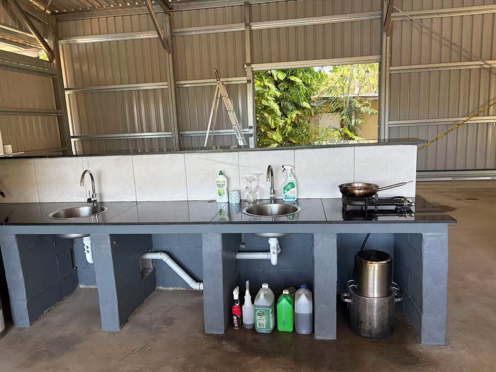 Una cocina con dos fregaderos, una estufa y armarios de almacenamiento.