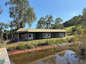 A two-story building with a flat roof, surrounded by trees and a pond. - Sunshine Gardens FarmStay (South Mission Beach)
