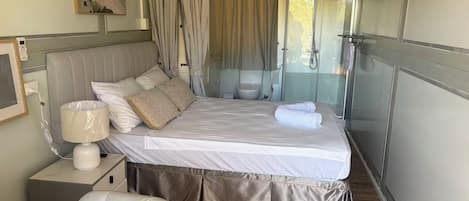 A bedroom with a bed, bedside table, lamp, and a chair.