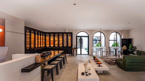 Uma sala de estar moderna com cozinha, apresentando uma mesa de jantar grande, um sofá e uma mesa de centro.