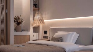 Quarto moderno com uma cama grande, mesa de cabeceira e um vaso decorativo.