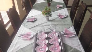 A dining table set with pink napkins, plates, and cutlery, and a tray with wine glasses.