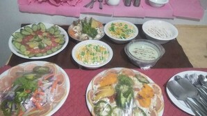 A table with various dishes, including salads and bowls of food, set on a tablecloth.