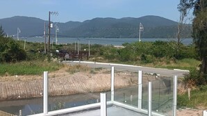 Een brug met een glazen balustrade, een onverhard pad en een waterpartij met bergen op de achtergrond.