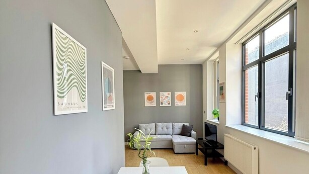 A modern living room with a white table, grey walls, and a large window. - Shoreditch Apartments by PrimeCityHosts F4 (Greater London)