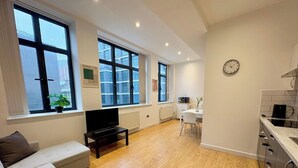 A modern apartment with a living area, kitchenette, and large windows. - Shoreditch Apartments by PrimeCityHosts F4 (Greater London)