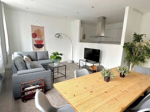 Ein modernes Wohnzimmer mit einem grauen Sofa, einem Holzesstisch und einem Fernsehschrank.
