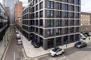 Un immeuble moderne à plusieurs étages, avec un parking situé devant.