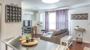 A modern living room with a sofa, a dining table, and a kitchen area with a TV.