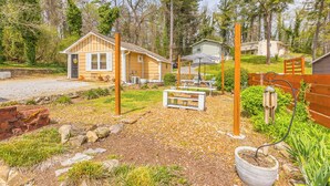 A rustic cabin with a porch, a small shed, and a picnic table.