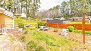 A residential backyard with a picnic table, outdoor seating, a fire pit, and a wooden fence.