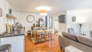 A modern kitchen with a dining area, a sofa, and a small table with chairs.