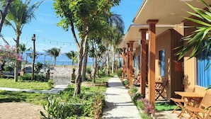 Et strandhotel med trækonstruktioner, en sti og frodig, tropisk vegetation.